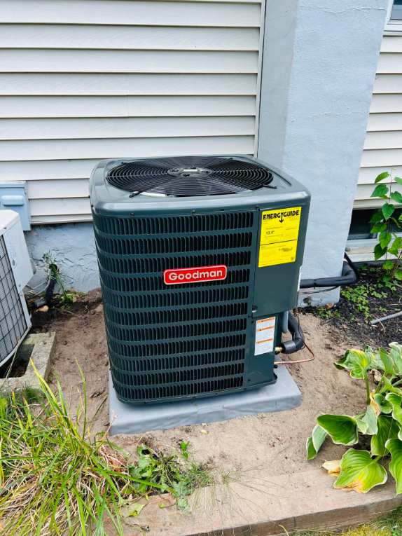 Goodman condenser installed at a house corner by Cool Temp